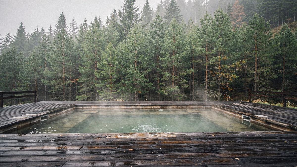 Mineral spa pool and wooden deck at a Carpathian retreat surrounded by pine forest